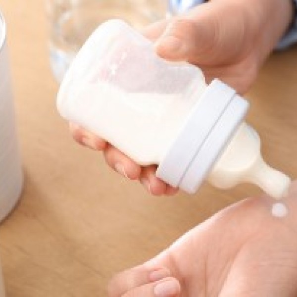 Close up of someone testing the temperature of prepared baby formula on their wrist.
