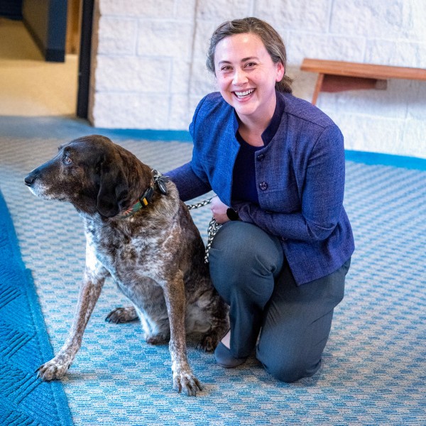 a woman crouches to pet a dog