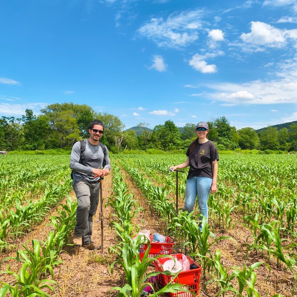 Two people standing in a field with equipment.