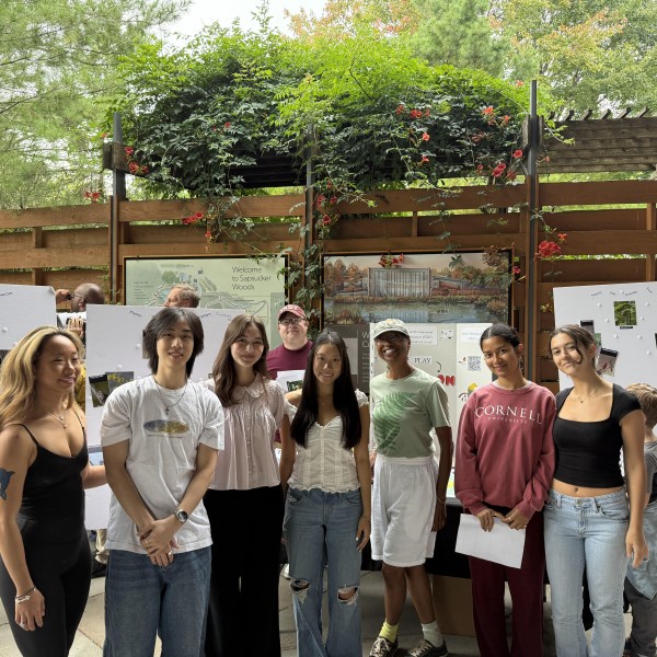 group of students stand in front of poster boards, smiling