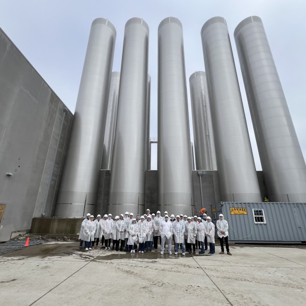 image of dairy workers in PPE standing outside a dairy plant