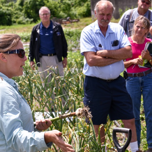 Crystal Stewart Courtens at CCE field day holding garlic and speaking to attendees