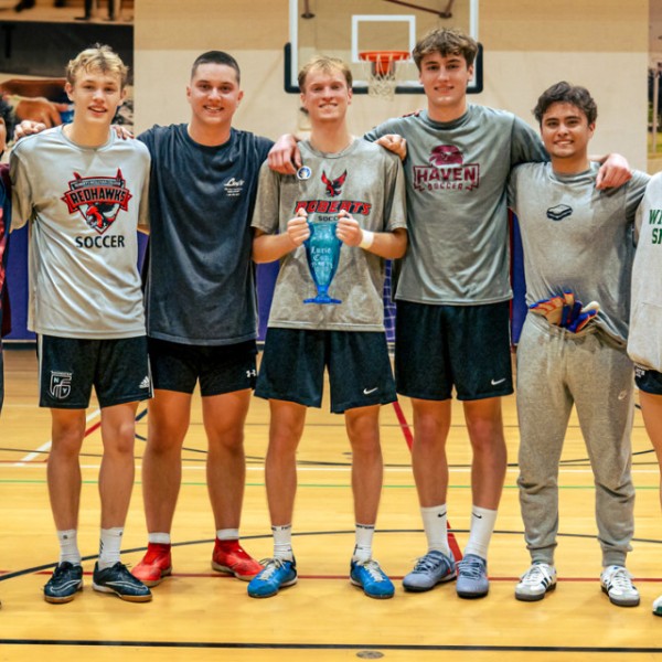 Basketball plays pose on a basketball court with their trophy. 
