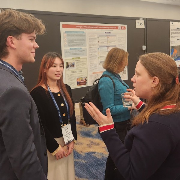 three individuals stand in front of a poster board