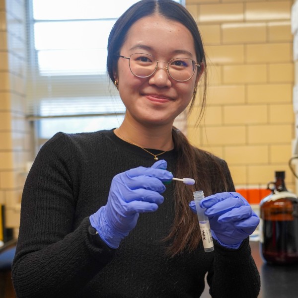 a woman holds a vial of liquid in a lab