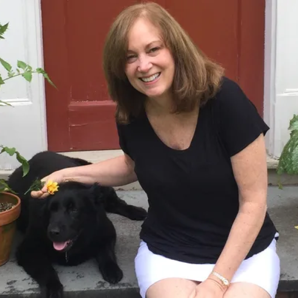 dawn Schrader sitting in front of a door petting a dog