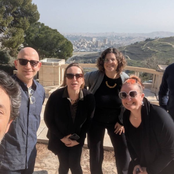 5 individuals stand and smile for a selfie