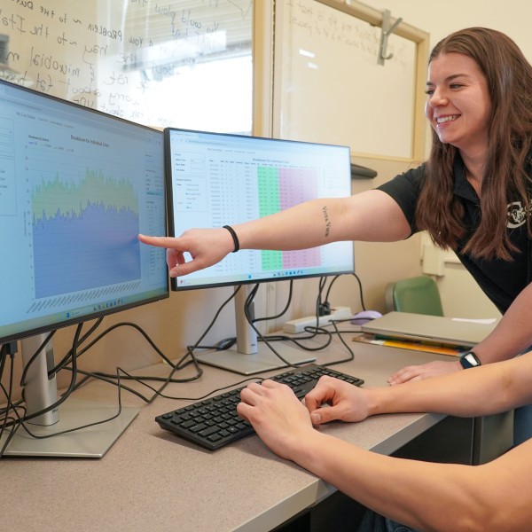 a woman points out data on a screen to a man