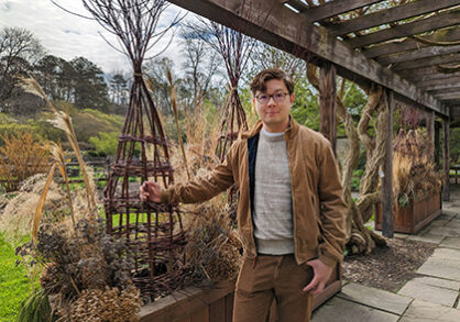 Man standing by willow sculpture in garden
