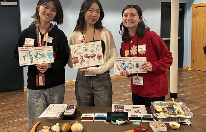 Three college students showing project at a table.