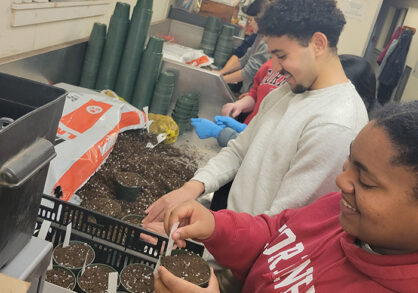 two students smiling while putting bulbs